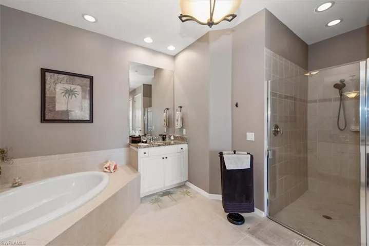 Full bathroom featuring light tile patterned floors, vanity, a shower stall, a garden tub, and recessed lighting