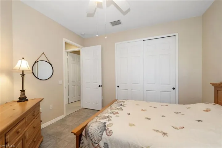 Bedroom with ceiling fan, a closet, and light tile patterned floors