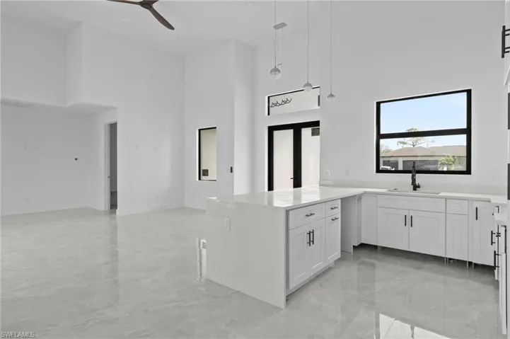 Kitchen featuring a high ceiling, white cabinetry, sink, and decorative light fixtures