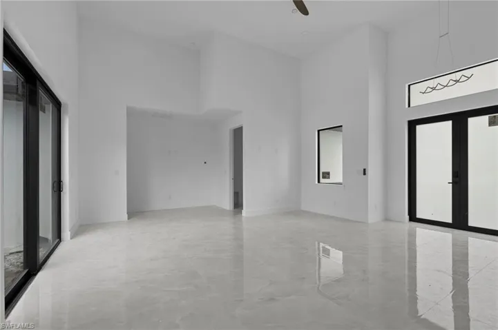 Empty room featuring french doors, a towering ceiling, and ceiling fan