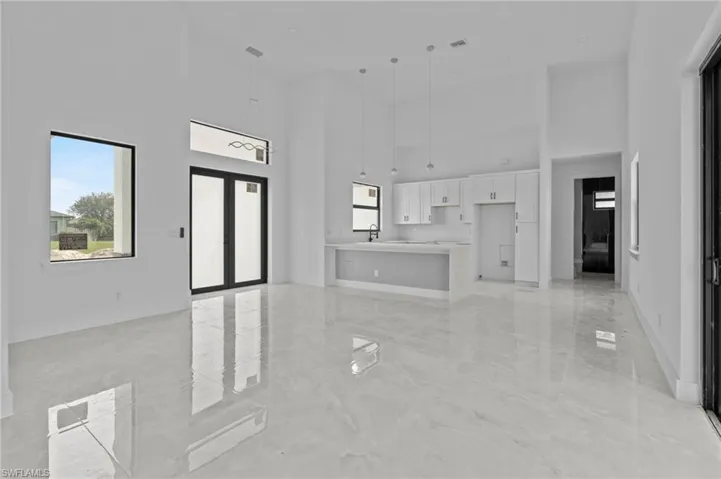 Unfurnished living room with sink, a towering ceiling, and french doors