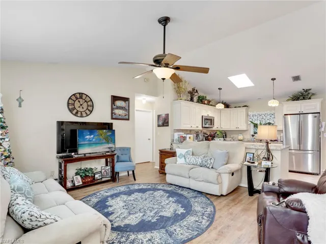 Living room featuring ceiling fan, light hardwood / wood-style flooring, and lofted ceiling with skylight