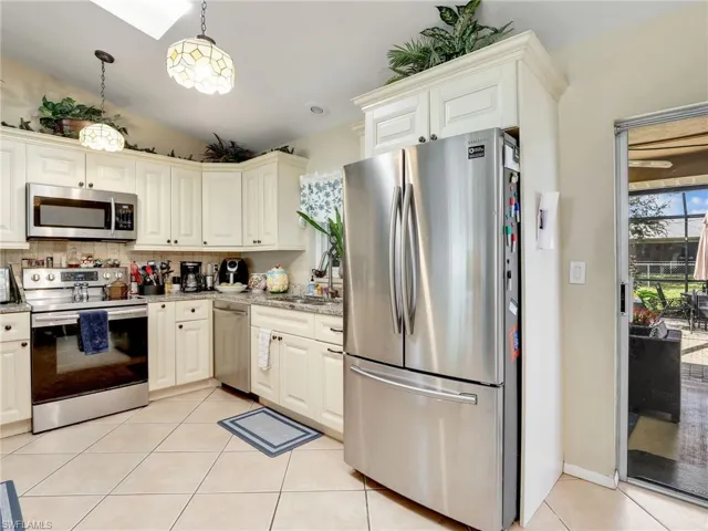 Kitchen with tasteful backsplash, light tile flooring, pendant lighting, sink, and appliances with stainless steel finishes