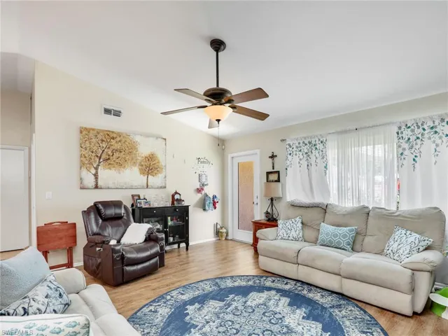 Living room featuring wood-type flooring, ceiling fan, and lofted ceiling