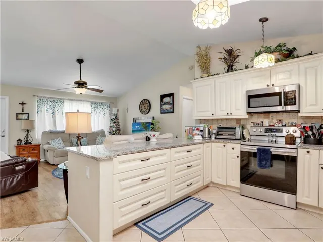 Kitchen with decorative light fixtures, kitchen peninsula, range with electric cooktop, ceiling fan, and light wood-type flooring