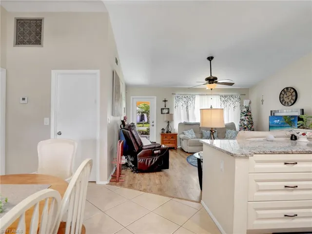 Kitchen with white cabinetry, light stone countertops, ceiling fan, and light tile floors