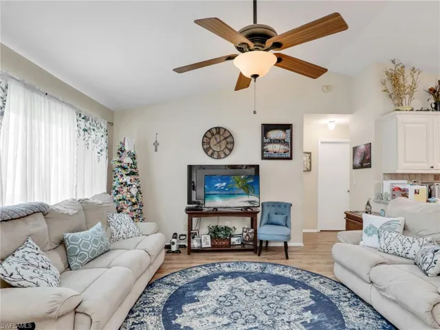 Living room featuring ceiling fan, light wood-type flooring, and lofted ceiling