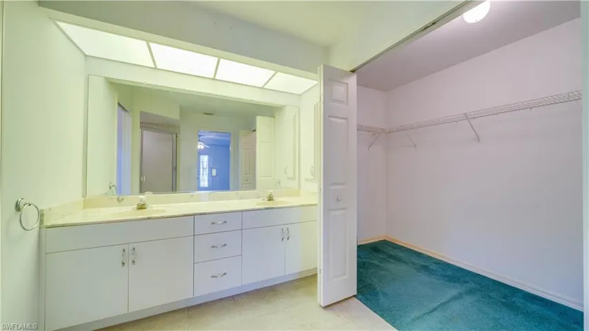 Bathroom featuring a walk-in closet and double vanity/sinks.