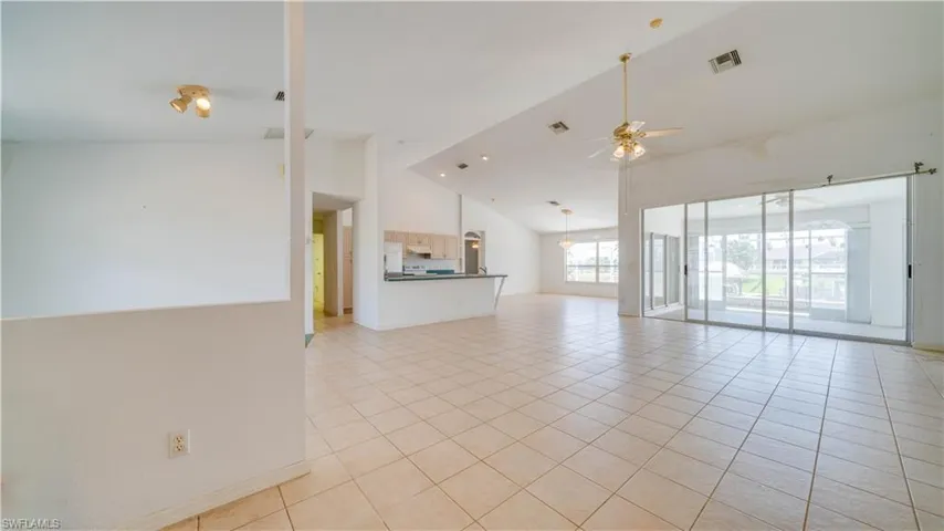 View of Great Room from entryway. Large open space with many windows & sliding doors providing a bright and airy atmosphere. High vaulted ceilings throughout!
