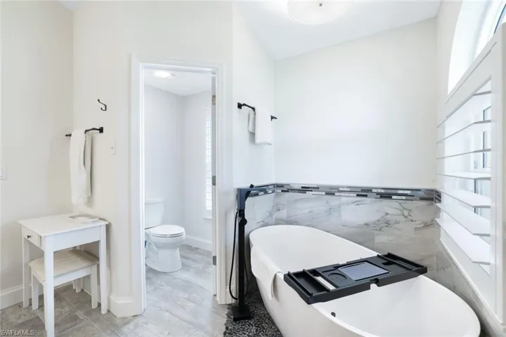 Bathroom with toilet, hardwood / wood-style flooring, and a bath