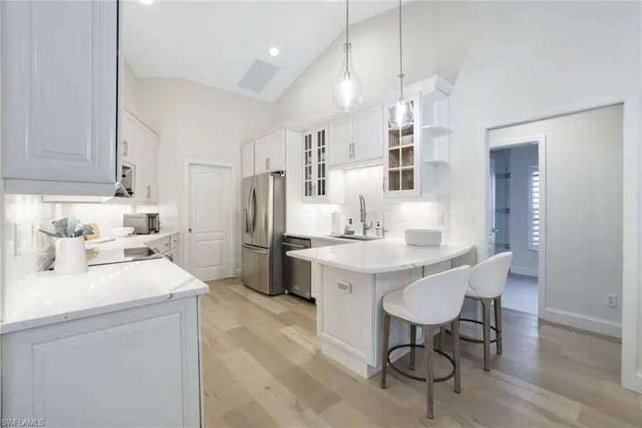 Kitchen featuring appliances with stainless steel finishes, tasteful backsplash, kitchen peninsula, and light wood-type flooring