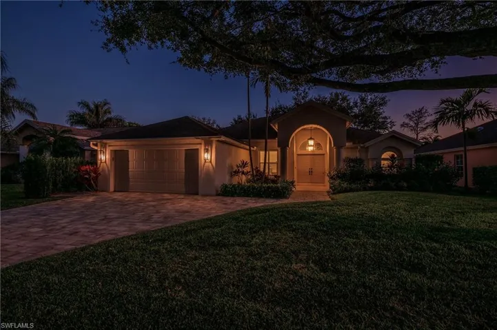 View of front of property with a garage and a yard