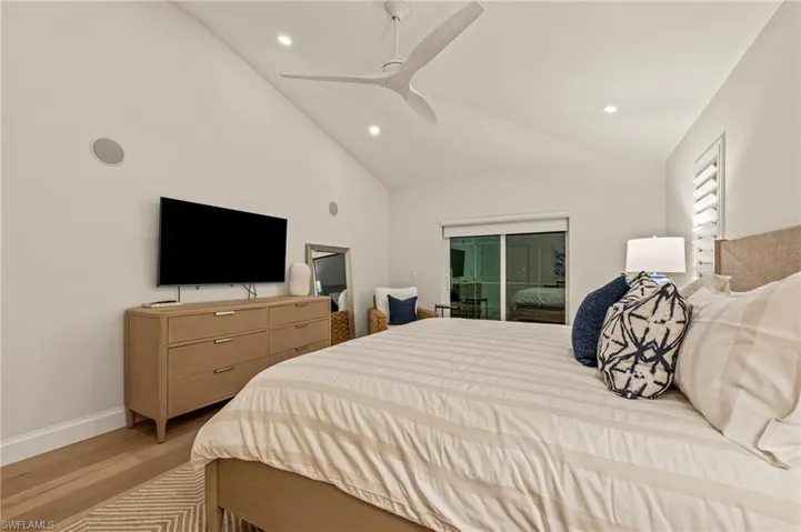 Bedroom with ceiling fan, lofted ceiling, and light wood-type flooring