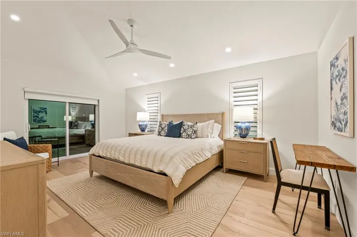Bedroom featuring light hardwood / wood-style flooring, access to exterior, vaulted ceiling, and ceiling fan