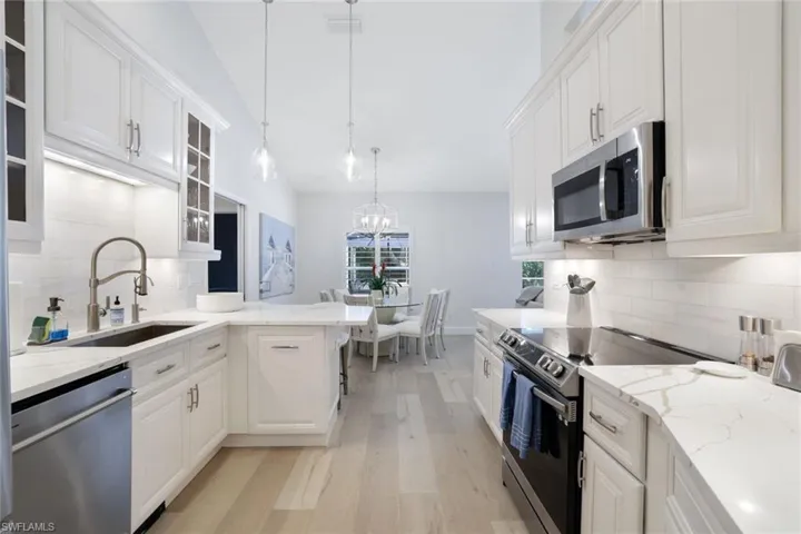 Kitchen featuring appliances with stainless steel finishes, tasteful backsplash, sink, light wood-type flooring, and white cabinetry