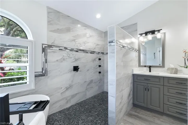 Bathroom with vanity, tiled shower, hardwood / wood-style floors, and tile walls