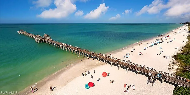 Birds eye view of property with a water view and a beach view