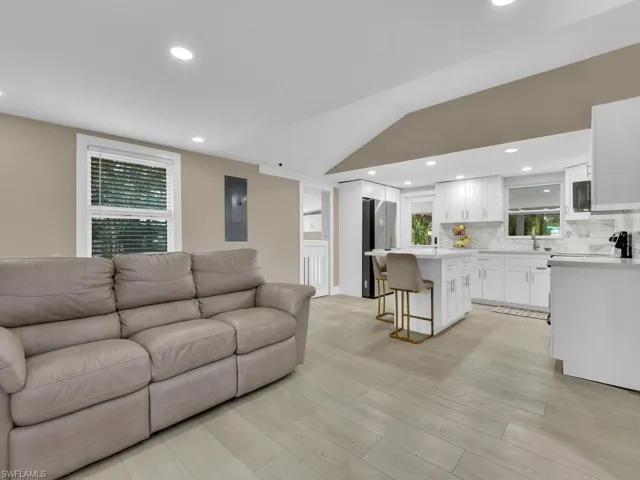 Living area featuring lofted ceiling, recessed lighting, light wood-style flooring, and electric panel