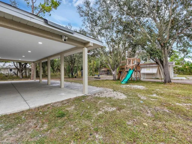 View of grassy yard with a playground and a patio area