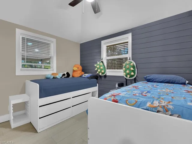 Bedroom with wood walls, a ceiling fan, and light wood-style flooring