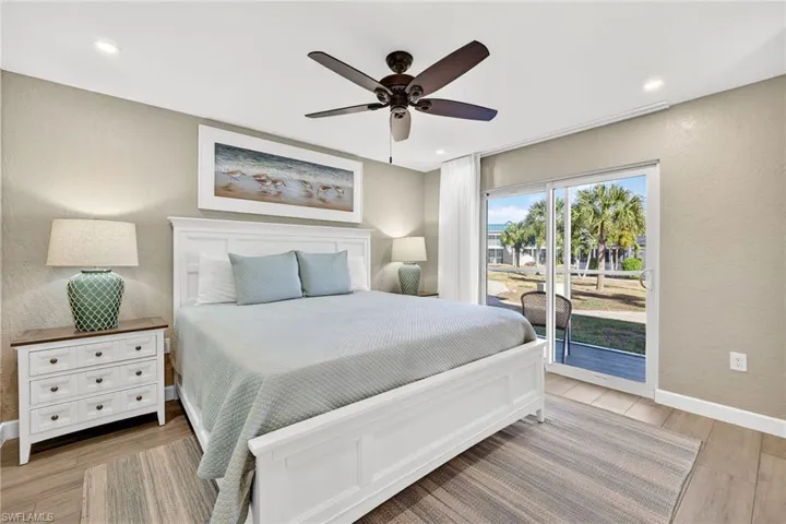 Bedroom featuring a textured wall, access to exterior, light wood-style flooring, a ceiling fan, and recessed lighting