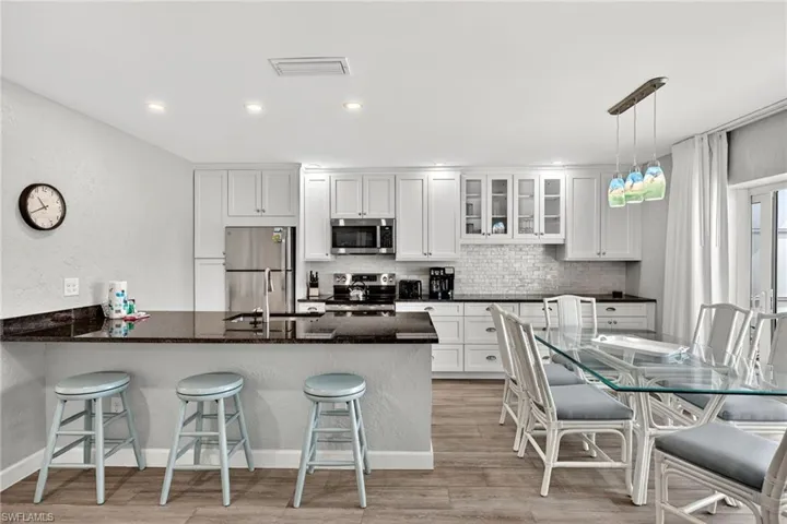 Kitchen with a kitchen breakfast bar, glass insert cabinets, a textured wall, a peninsula, and stainless steel appliances