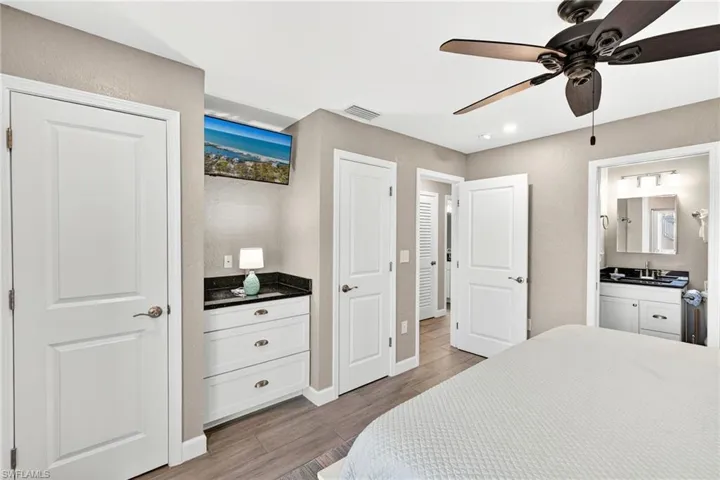 Bedroom featuring two closets, light wood-style flooring, a ceiling fan, ensuite bathroom, and recessed lighting