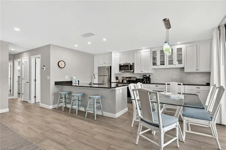 Kitchen featuring a peninsula, a kitchen breakfast bar, stainless steel appliances, glass insert cabinets, and white cabinets