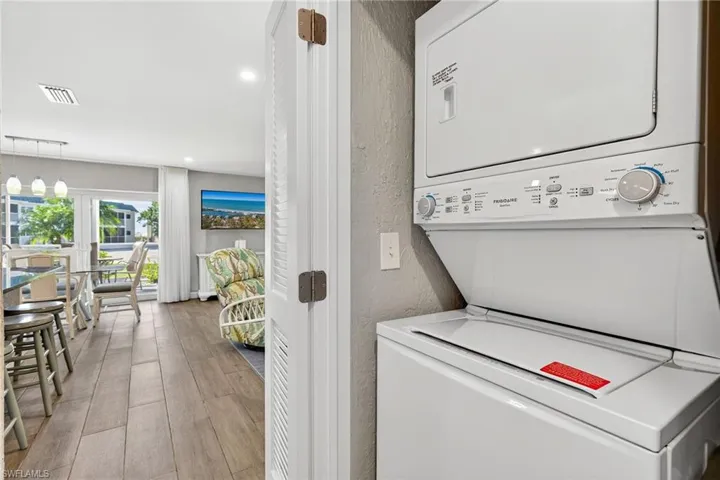 Washroom featuring light wood finished floors, recessed lighting, stacked washer / dryer, and a textured wall