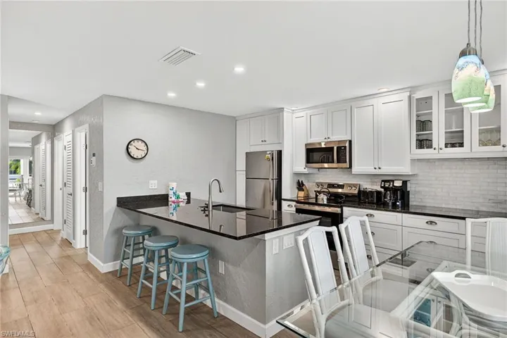Kitchen with a breakfast bar, a peninsula, stainless steel appliances, dark stone countertops, and glass insert cabinets