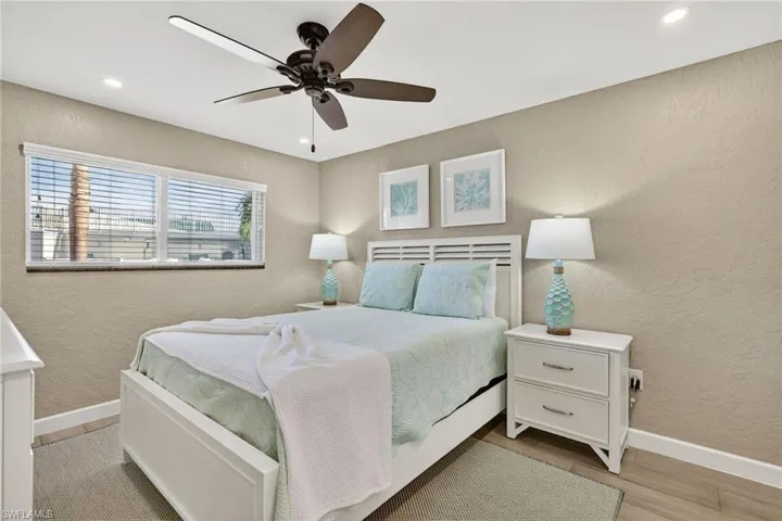 Bedroom with a textured wall, ceiling fan, recessed lighting, and light wood-style flooring
