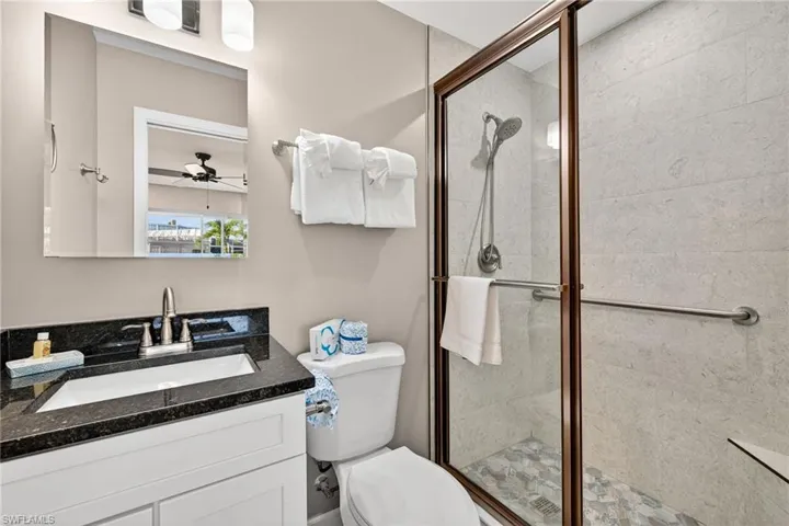 Bathroom featuring vanity, a stall shower, and ceiling fan
