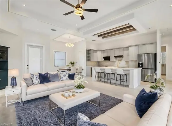 Living area with ceiling fan, a chandelier, recessed lighting, and a tray ceiling