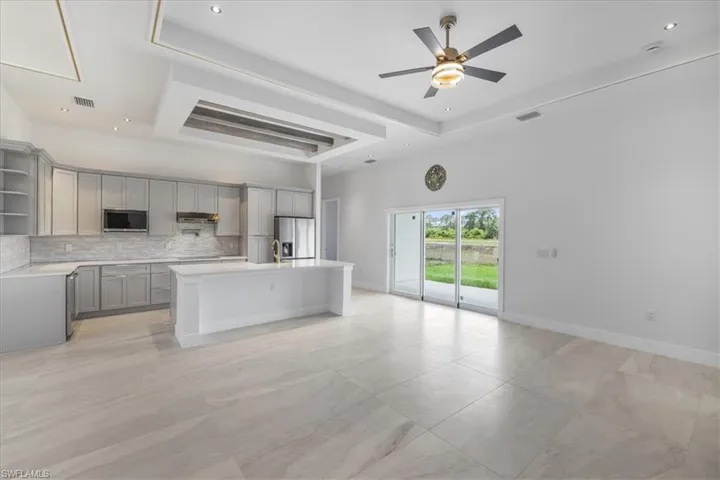 Kitchen featuring gray cabinetry, stainless steel appliances, open shelves, a raised ceiling, and recessed lighting