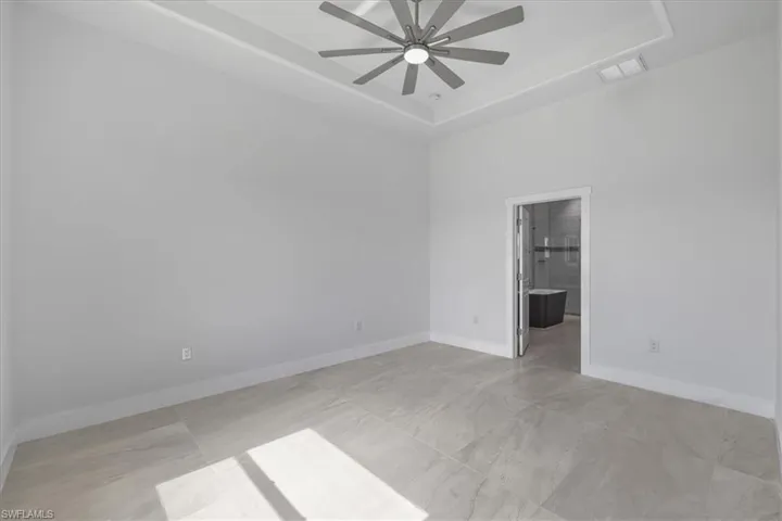 Unfurnished room featuring a raised ceiling and a ceiling fan