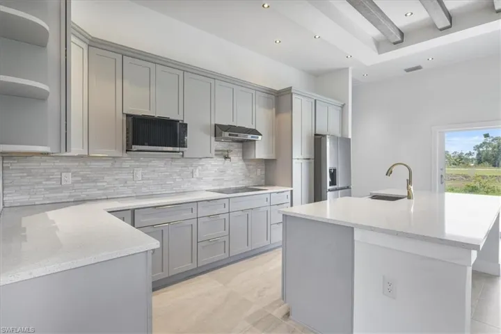 Kitchen with appliances with stainless steel finishes, gray cabinets, tasteful backsplash, light stone countertops, and recessed lighting