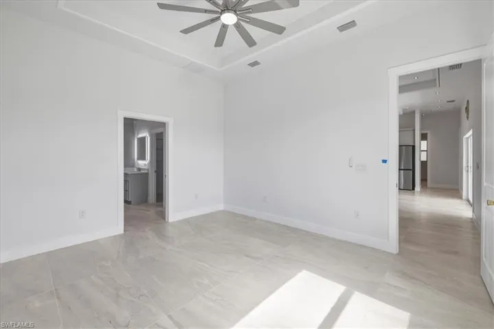 Empty room featuring a ceiling fan and a raised ceiling