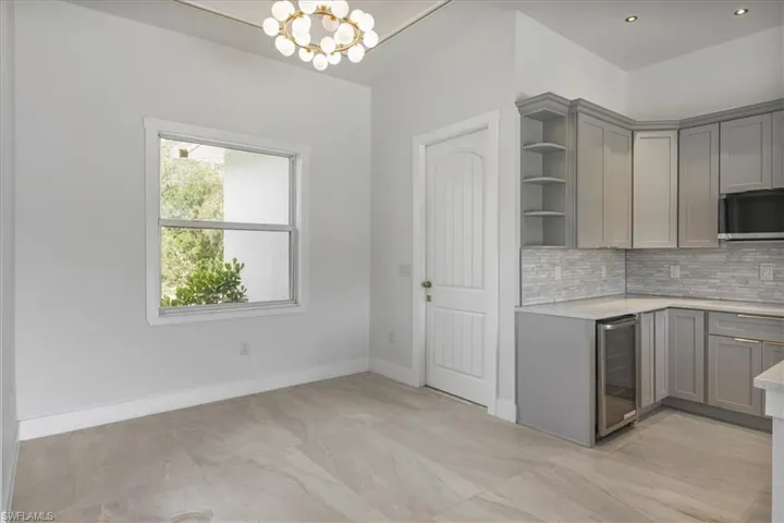 Kitchen with gray cabinets, open shelves, wine cooler, light countertops, and decorative backsplash