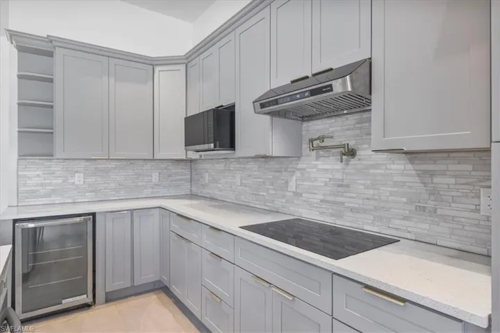 Kitchen featuring beverage cooler, exhaust hood, black appliances, open shelves, and gray cabinetry