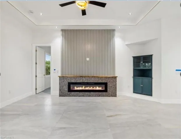 Unfurnished living room with ceiling fan, a glass covered fireplace, and recessed lighting