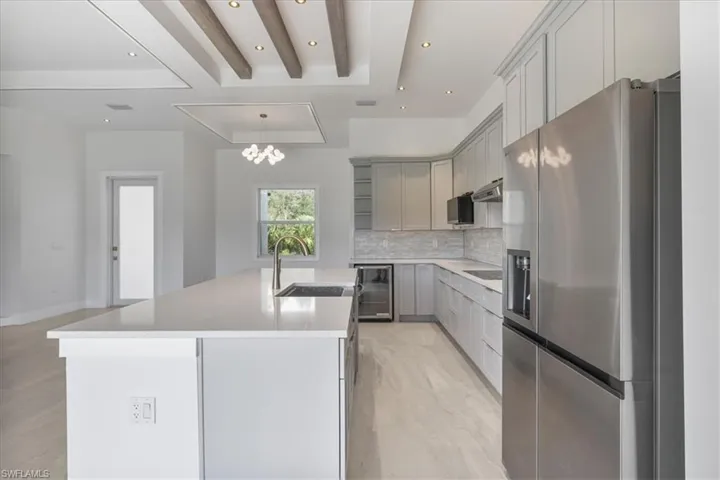 Kitchen with stainless steel fridge with ice dispenser, gray cabinetry, backsplash, an island with sink, and wine cooler