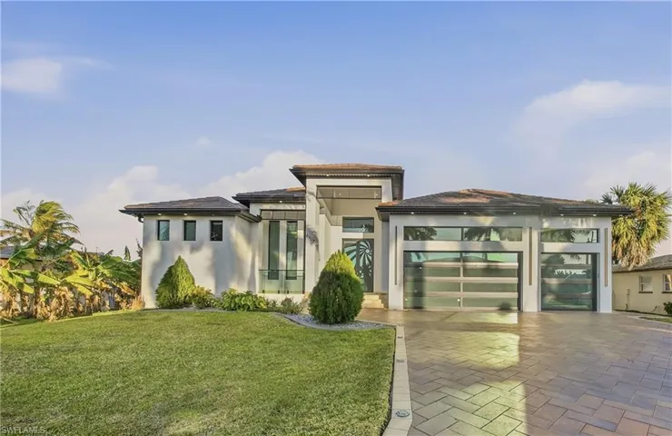 Prairie-style house with a front lawn, stucco siding, decorative driveway, and an attached garage