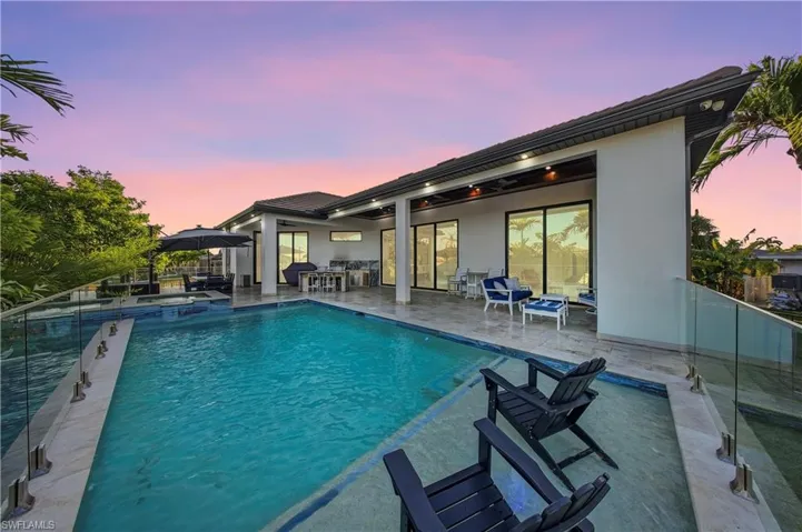 Pool at dusk with a patio area and a pool with connected hot tub