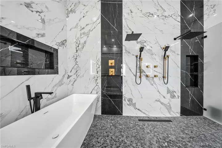 Master Bathroom featuring a soaking tub, a marble finish shower, stone wall, and tile walls