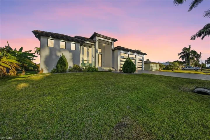 Contemporary house featuring driveway, a front lawn, stucco siding, and a garage