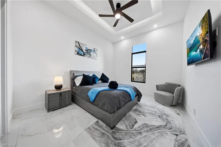 Bedroom featuring ceiling fan, a tray ceiling,