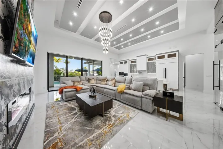 Living room featuring chandelier, high ceiling, wall with fire place.