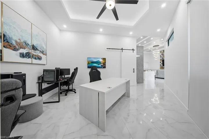 Office area featuring a barn door, recessed lighting, a raised ceiling, a ceiling fan,