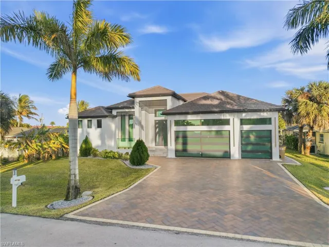 View of front facade featuring a front yard, stucco siding, a 3 car garage, decorative driveway, and a tile roof