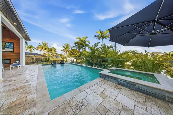 Combined pool / hot tub with a patio area and a fenced backyard